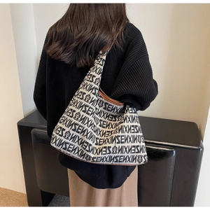 Close-up of knit tote bag featuring black SENXIN lettering and leather trim on model