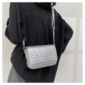 Silver metallic crossbody bag with round stud rivets and woven strap worn by a model