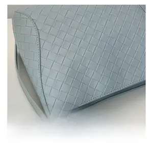 Detail of light blue-grey woven PU leather texture with metal chain and pearl charm