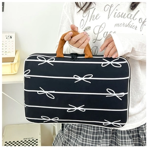 Detail of laptop bag showing white bow pattern, brown handle and dual zipper closure