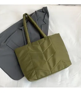 Detail of olive green quilted nylon tote bag with V-shaped stitching on white fabric