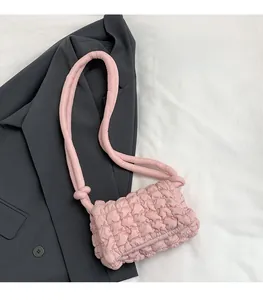 Detail einer hellrosa gesteppten Nylon-Schultertasche mit weicher Faltenstruktur und Knoten