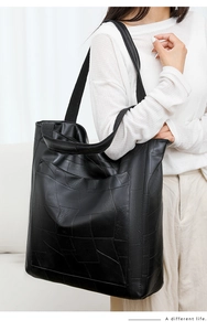 Close-up of a large black patchwork PU leather tote bag showing texture and strap details