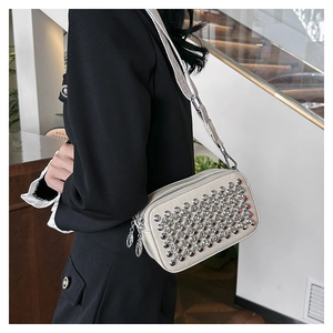 Detail of off-white PU leather crossbody bag featuring silver stud rivets and leaf zipper