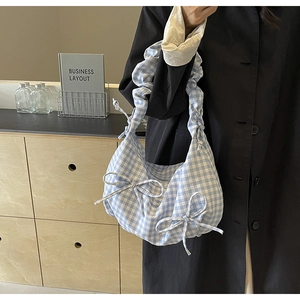 Detailed view of gingham cotton shoulder bag featuring bow accents and ruffled strap design