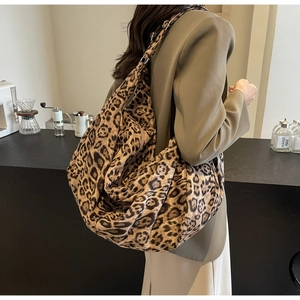 Detailed close-up of a large leopard print tote bag worn on shoulder in a cafe setting
