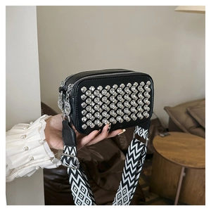 Detail of a vintage diamond-studded crossbody bag with stylish patterned wide strap