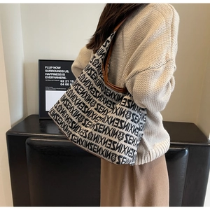 Detail of knitted tote bag featuring SENXIN bear pattern and brown leather straps