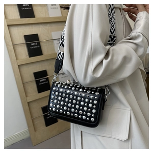 Detail of black crossbody bag with silver studs and a geometric patterned wide strap