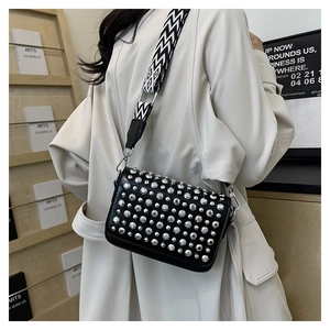 Detail of black PU crossbody bag with silver studs and geometric wide strap on model