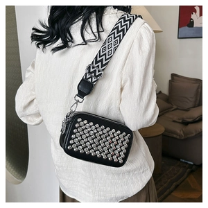 Close-up of black crossbody bag with silver rhinestones and wide geometric fabric strap