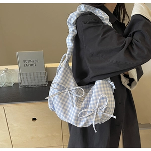 Detail of blue gingham shoulder bag featuring bow accents and ruffled strap design