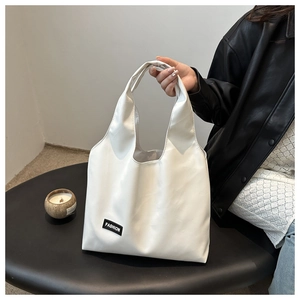 Detail shot of the white PU leather tote bag featuring a black fashion label and texture