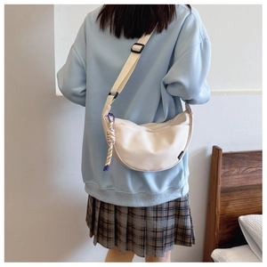 Detail of minimalist beige nylon half-moon crossbody bag with colorful rope charm