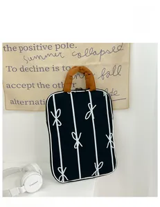 Detail of black striped laptop tote bag with bow design and brown handles on a white background