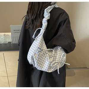 Detail of blue gingham fabric shoulder bag with decorative bows and ruffled strap