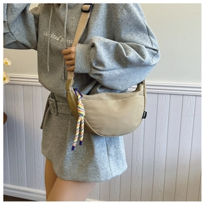 Detail of khaki crescent crossbody bag in canvas with colorful rope and fashion tag