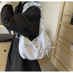 Detail of blue and white checkered canvas tote bag with bow accents and ruffled shoulder strap