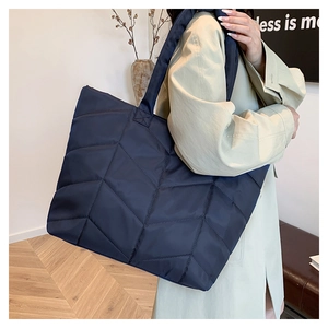Detail view of navy blue quilted nylon tote bag with herringbone pattern and plush texture