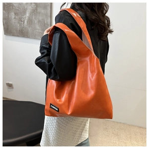 Close-up of vibrant orange PU leather hobo bag with Fashion label in modern interior
