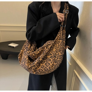 Close-up of leopard print canvas crossbody bag with adjustable strap and metal buckle