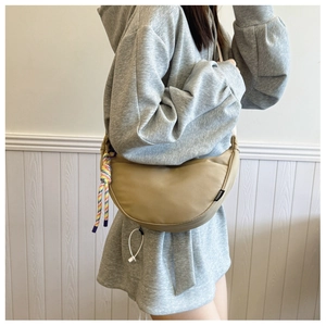 Detail view of khaki crescent shoulder bag with colorful woven strap and fashion label
