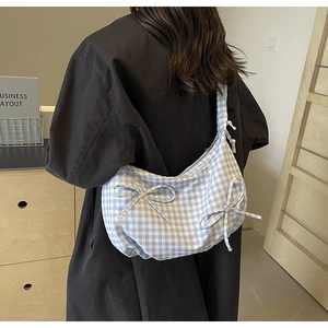 Detail of blue and white checkered canvas shoulder bag with decorative bows