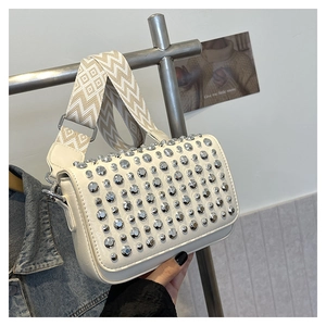 White PU leather shoulder bag with silver studs and a geometric woven strap shown on display