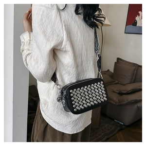 Detailed view of black PU leather crossbody bag with silver skull stud embellishments