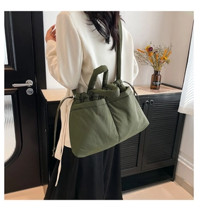 Close-up of dark green quilted tote bag with drawstring closure and shoulder straps