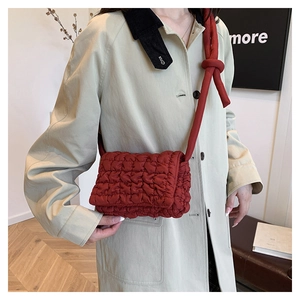 Detail einer roten gesteppten Puffy-Tasche mit modischem Dekoknoten am Nylon-Schultergurt
