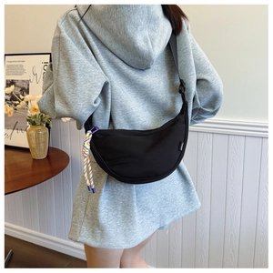 Detail view of black nylon crescent shoulder bag with adjustable strap and rainbow pendant