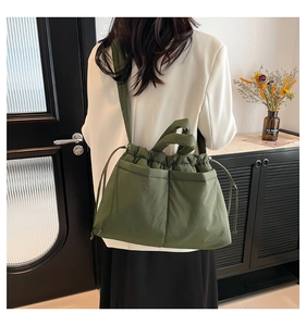 Detail of dark green puffy tote bag with drawstring closure and two front pockets