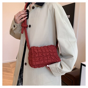 Detail einer roten gesteppten Nylon-Schultertasche mit dekorativem Knotengurt am Model
