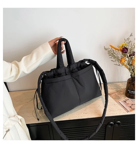 Detail view of black quilted fabric tote bag with shoulder strap and side pockets