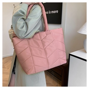 Detailed view of pink quilted nylon tote bag with V-shaped stitching on a female model
