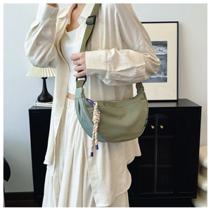 Detail of olive green crescent fabric bag featuring a woven charm and fashion side label