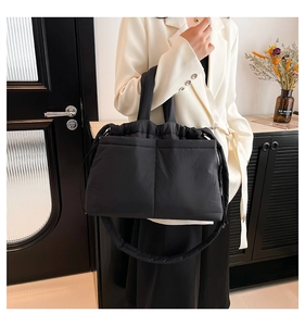 Detail of black quilted puffer tote bag with drawstring closure and adjustable strap