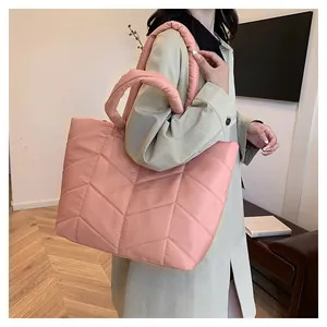 Detailed street style view of a pink quilted nylon puffer tote bag on shoulder