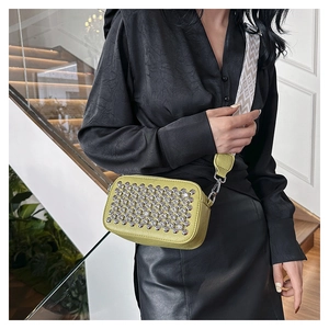 Detailed view of yellow-green PU leather bag with silver studs and geometric strap