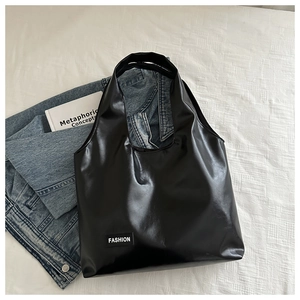 Elegant black high-gloss PU leather tote bag with Fashion label on white texture
