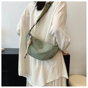 Detail of light olive nylon crescent bag with woven rope charm and fashion label