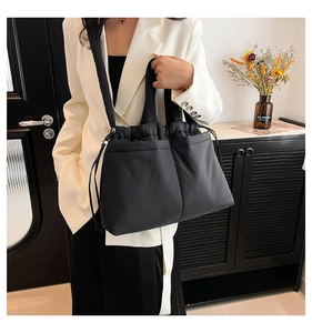 Detail of black quilted puffer tote bag featuring drawstring closure and side pocket