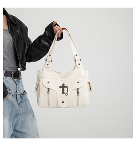 Detail einer cremeweißen PU-Leder Hobo-Tasche mit Punk-Metallkreuzen und Kettenanhängern