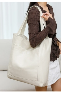 Detail view of large white PU tote bag with geometric embossed texture on shoulder