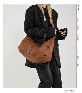 Détail d'un grand sac hobo marron avec texture en cuir grainé et boucles métalliques chic
