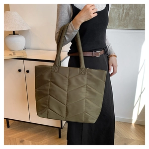 Detail of olive green quilted nylon tote bag with V-shaped stitching and long shoulder straps