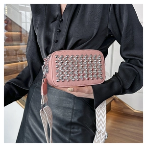 Close-up of pink PU leather crossbody bag featuring silver studs and a woven shoulder strap