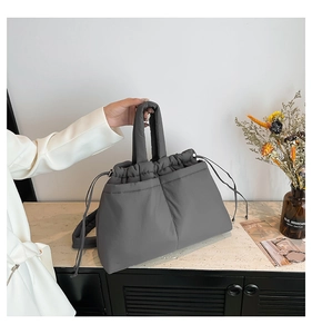 Detail of grey quilted down tote bag featuring drawstring closure and soft nylon texture