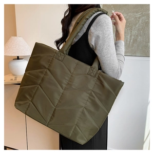 Army green quilted nylon tote bag worn by model in a minimalist modern home setting